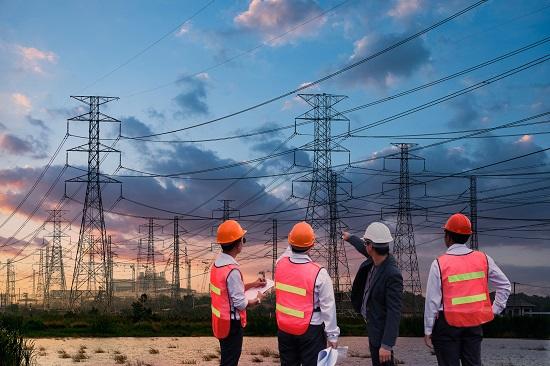 Silhouette high voltage electric tower and engineer team on sunset time and sky on sunset time background.